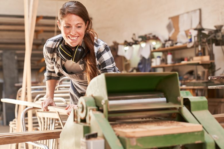 Vrouw bewerkt hout in een werkplaats