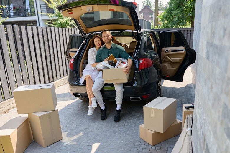 stel met verhuisdozen en private lease auto voor hun nieuwe huis
