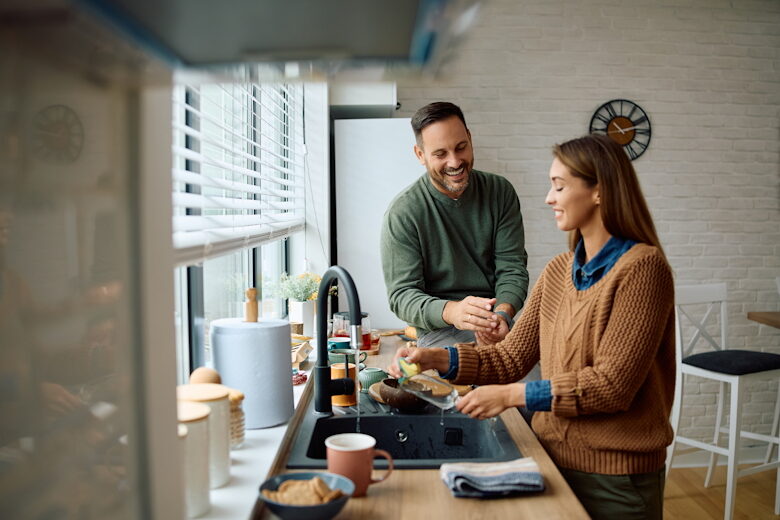 Man en vrouw in de keuken van hun huis, pratend bij het aanrecht