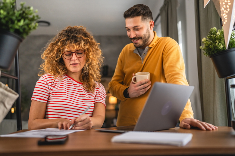 Man en vrouw nemen document door, naast laptop